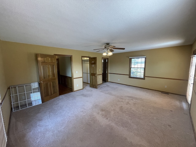 spare room featuring light carpet, a textured ceiling, and ceiling fan