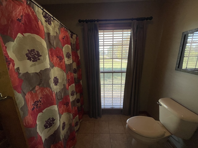 bathroom featuring toilet, a shower with shower curtain, tile patterned floors, and plenty of natural light