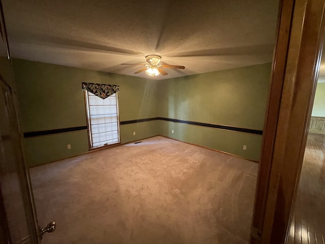 carpeted spare room with a textured ceiling and ceiling fan