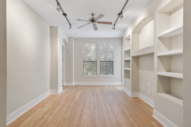 unfurnished living room featuring rail lighting, light hardwood / wood-style floors, built in shelves, and ceiling fan