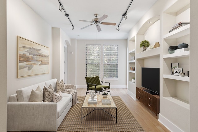 living room featuring light hardwood / wood-style flooring, track lighting, built in shelves, and ceiling fan