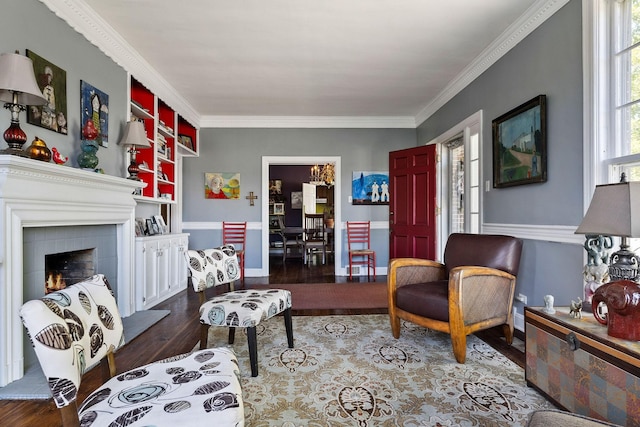 living area featuring ornamental molding, built in features, wood finished floors, and a warm lit fireplace