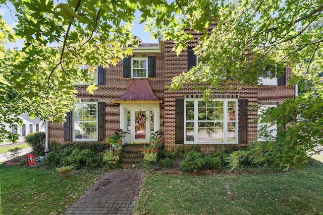 colonial inspired home featuring brick siding and a front yard