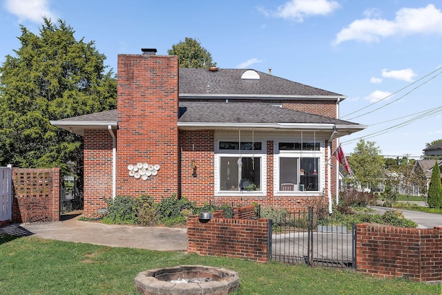 view of front of property with roof with shingles, brick siding, fence private yard, a chimney, and a fire pit
