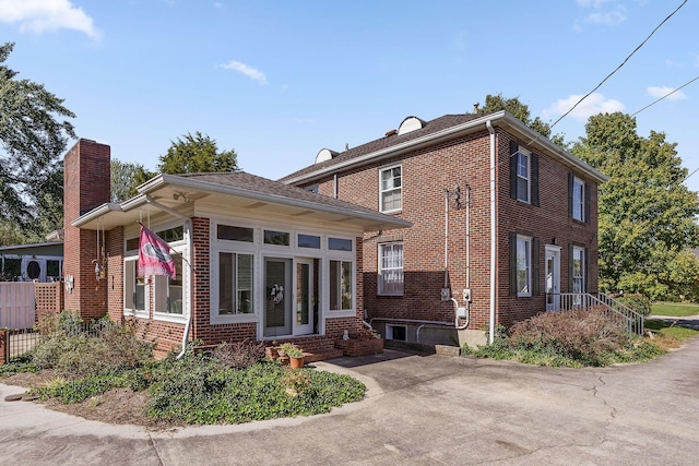 exterior space with brick siding, fence, a chimney, and entry steps