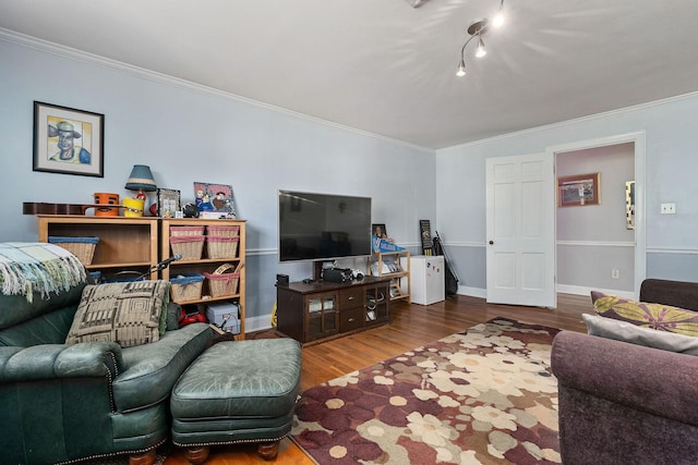 living area featuring baseboards, ornamental molding, rail lighting, and wood finished floors