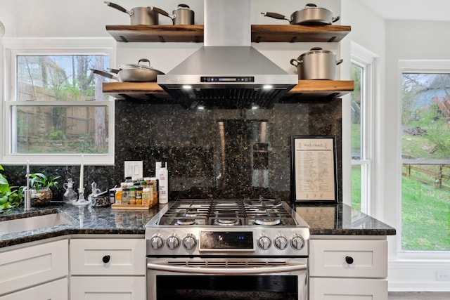 kitchen with decorative backsplash, stainless steel gas range, and white cabinets