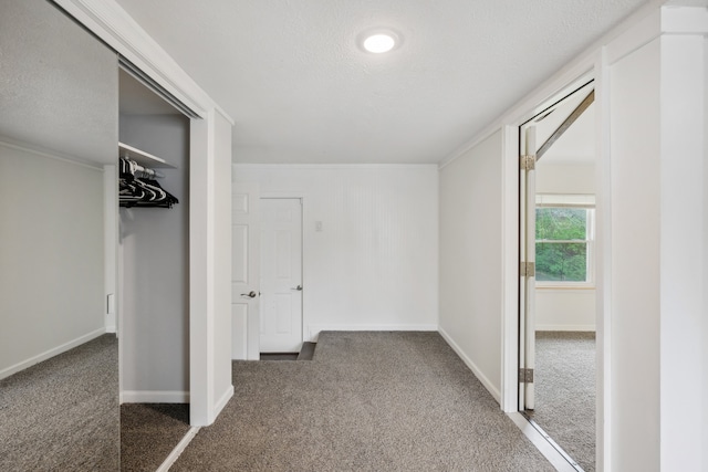 interior space with ornamental molding, a closet, a textured ceiling, and dark colored carpet