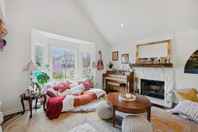 living room featuring a stone fireplace and high vaulted ceiling