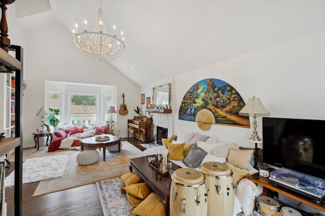 living room featuring an inviting chandelier, hardwood / wood-style floors, high vaulted ceiling, and a fireplace