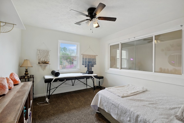 bedroom featuring ceiling fan, a textured ceiling, and dark carpet