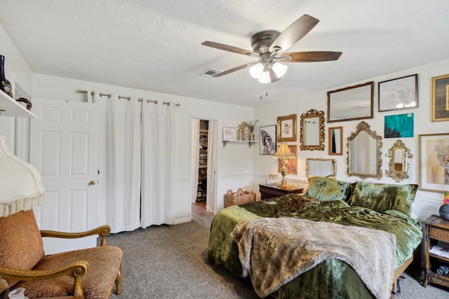 bedroom with ceiling fan, a textured ceiling, carpet floors, a closet, and a walk in closet