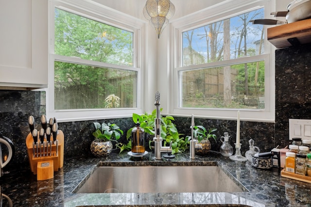 room details featuring white cabinetry, tasteful backsplash, sink, and dark stone counters