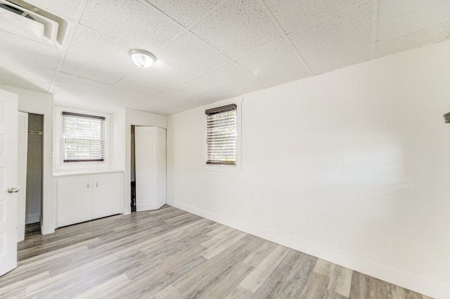 spare room featuring a paneled ceiling and light hardwood / wood-style flooring