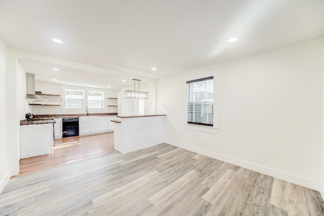 kitchen with beverage cooler, hanging light fixtures, white cabinetry, light wood-type flooring, and sink