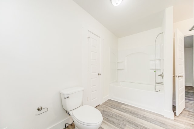 bathroom with toilet, wood-type flooring, and shower / tub combination