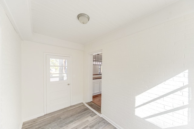 entrance foyer featuring brick wall and light hardwood / wood-style flooring