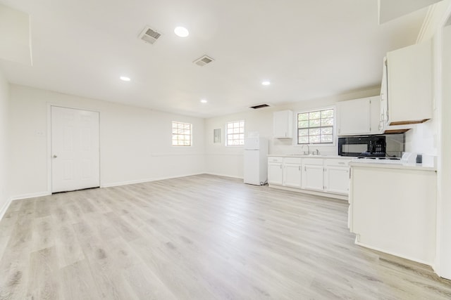 kitchen featuring white cabinetry, light hardwood / wood-style floors, sink, and white refrigerator