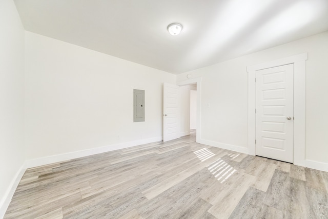 empty room featuring electric panel and light hardwood / wood-style floors