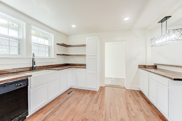 kitchen featuring black dishwasher, decorative light fixtures, white cabinetry, butcher block countertops, and light hardwood / wood-style floors