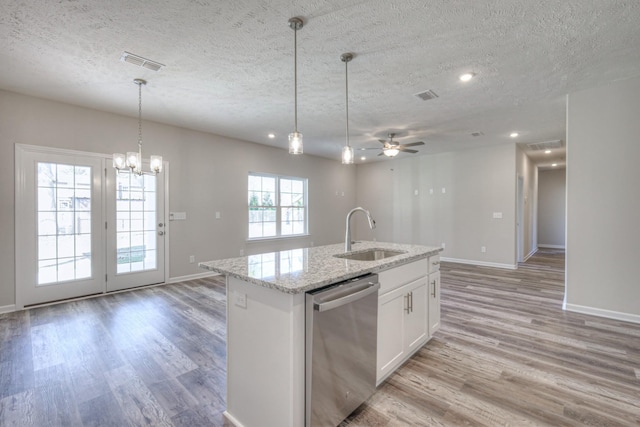 kitchen with a textured ceiling, stainless steel dishwasher, light stone countertops, a kitchen island with sink, and white cabinets