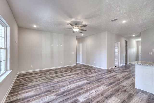 spare room featuring ceiling fan, dark hardwood / wood-style floors, a textured ceiling, and a wealth of natural light