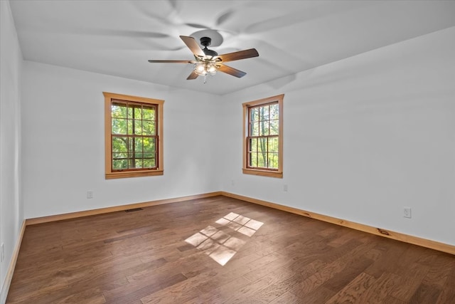 empty room featuring ceiling fan, dark hardwood / wood-style flooring, and plenty of natural light