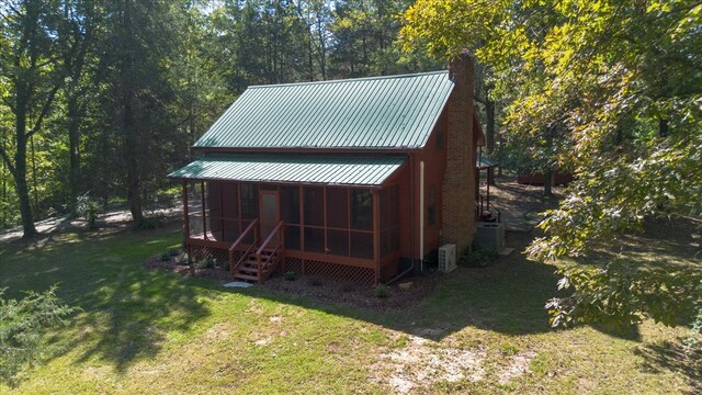 exterior space with a yard, a sunroom, and cooling unit