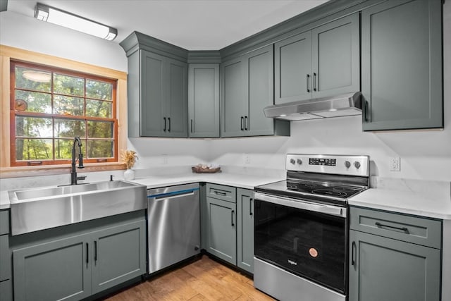 kitchen with light hardwood / wood-style flooring, gray cabinetry, stainless steel appliances, sink, and light stone countertops