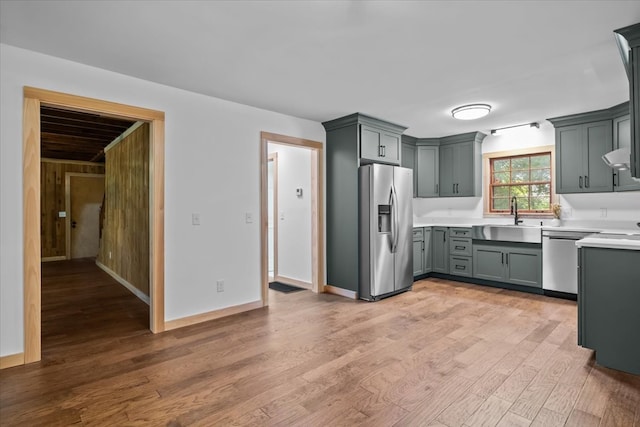 kitchen with appliances with stainless steel finishes, sink, gray cabinets, and light hardwood / wood-style floors