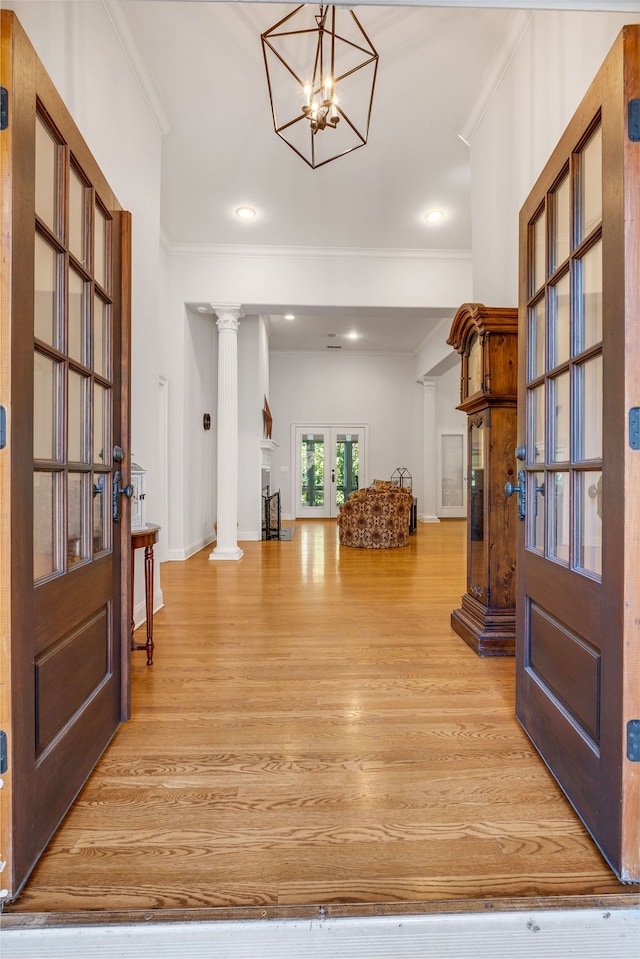 foyer featuring french doors, a notable chandelier, decorative columns, and hardwood / wood-style floors