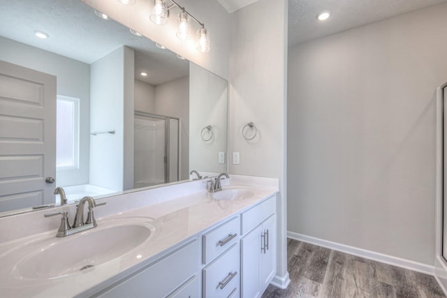 bathroom with vanity, wood-type flooring, plus walk in shower, and a textured ceiling