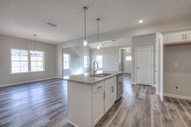 kitchen with white cabinetry, sink, light stone counters, and a kitchen island with sink