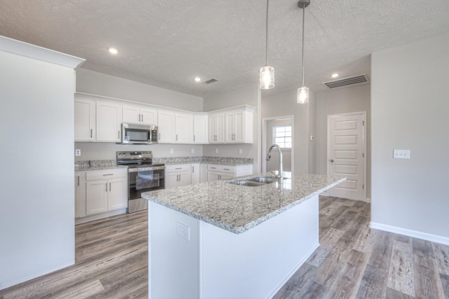 kitchen with sink, white cabinetry, a textured ceiling, appliances with stainless steel finishes, and an island with sink