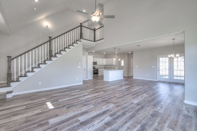 unfurnished living room with ceiling fan with notable chandelier, sink, hardwood / wood-style floors, and high vaulted ceiling