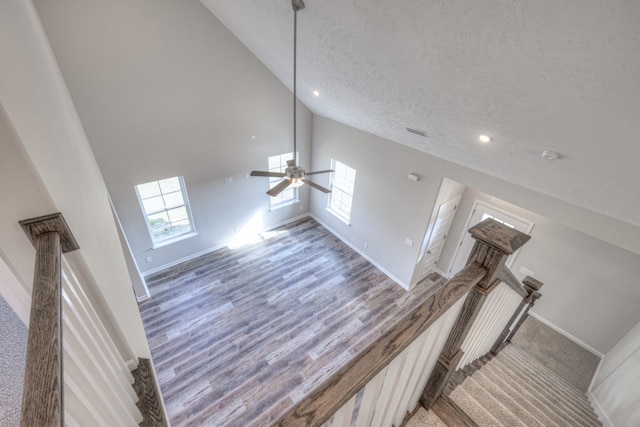 living room featuring ceiling fan, a towering ceiling, hardwood / wood-style floors, and a textured ceiling