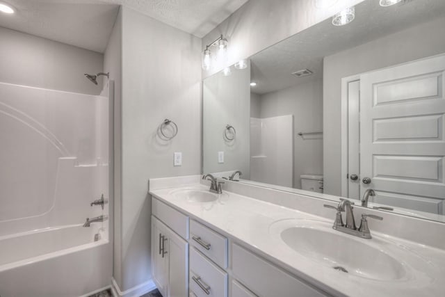 full bathroom with shower / tub combination, vanity, a textured ceiling, and toilet