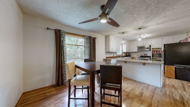 kitchen with sink, hanging light fixtures, white cabinetry, light hardwood / wood-style floors, and stainless steel appliances