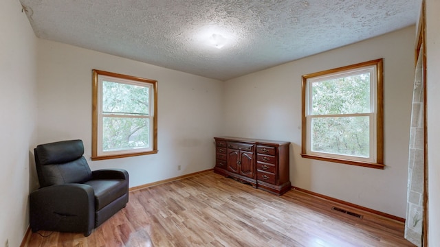 living area with a textured ceiling and light hardwood / wood-style flooring