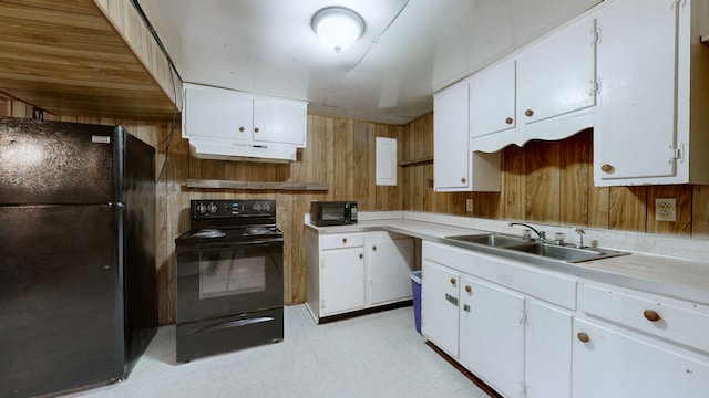 kitchen featuring wood walls, black appliances, sink, and white cabinets