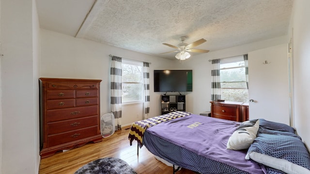 bedroom with light hardwood / wood-style flooring, multiple windows, a textured ceiling, and ceiling fan