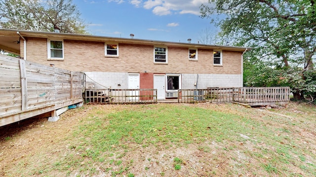 back of property with a deck and a lawn