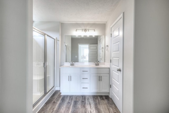 bathroom featuring an enclosed shower, hardwood / wood-style floors, vanity, and a textured ceiling