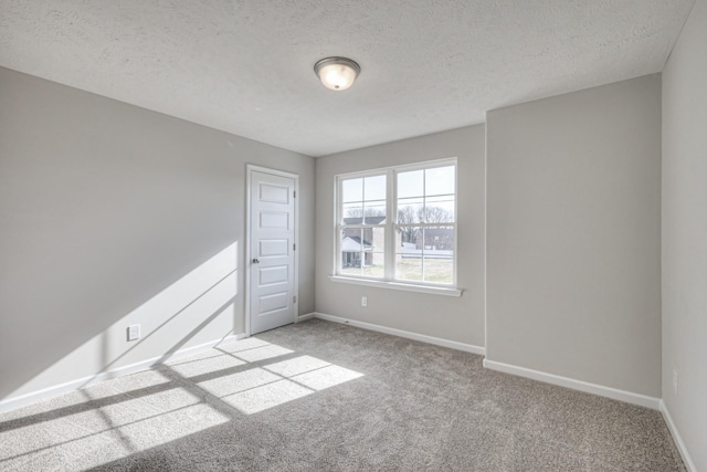 spare room with light colored carpet and a textured ceiling