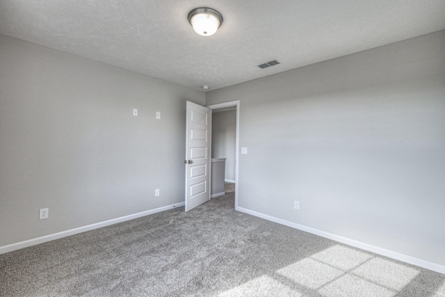 carpeted empty room with a textured ceiling