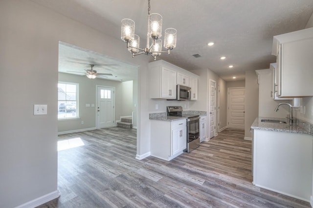 kitchen with sink, light wood-type flooring, white cabinets, and appliances with stainless steel finishes