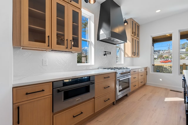 kitchen featuring light hardwood / wood-style floors, stainless steel appliances, wall chimney exhaust hood, and plenty of natural light