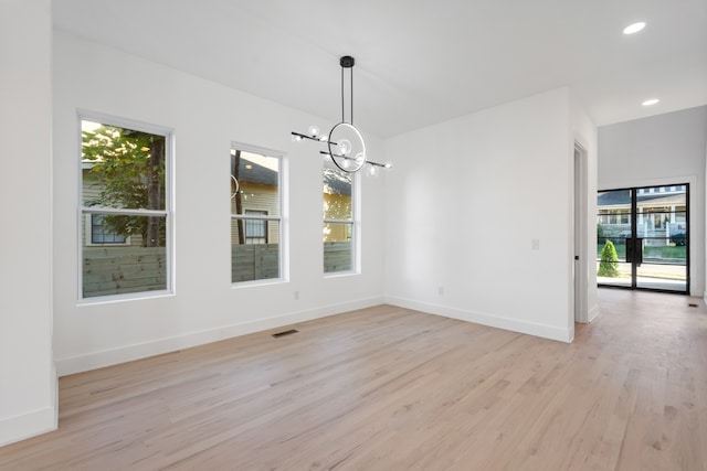 unfurnished dining area with light hardwood / wood-style floors, a notable chandelier, and a healthy amount of sunlight