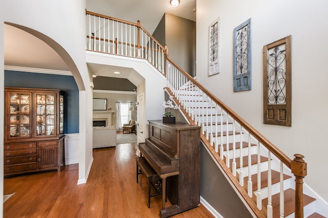 stairway featuring ornamental molding, a high ceiling, and hardwood / wood-style flooring