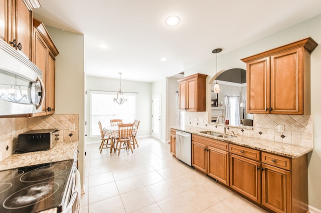 kitchen with appliances with stainless steel finishes, sink, decorative light fixtures, light stone counters, and decorative backsplash